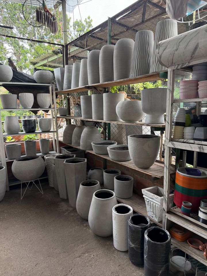 Estanterías llenas de materas de cemento gris y blanco de distintas formas y alturas