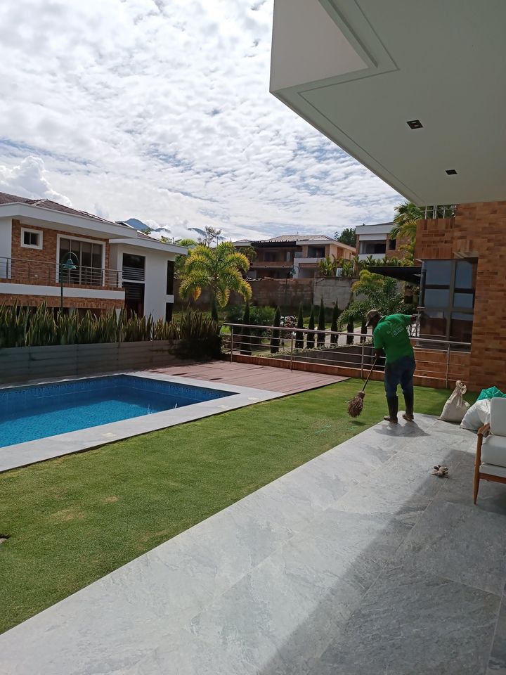 Prado recién instalado junto a una piscina, con lenguas de suegra y cipreses al fondo